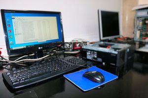 Taller de Dr. Windows: un ordinador obert en reparació al costat d'un lloc de treball amb pantalla, teclat i ratolí.